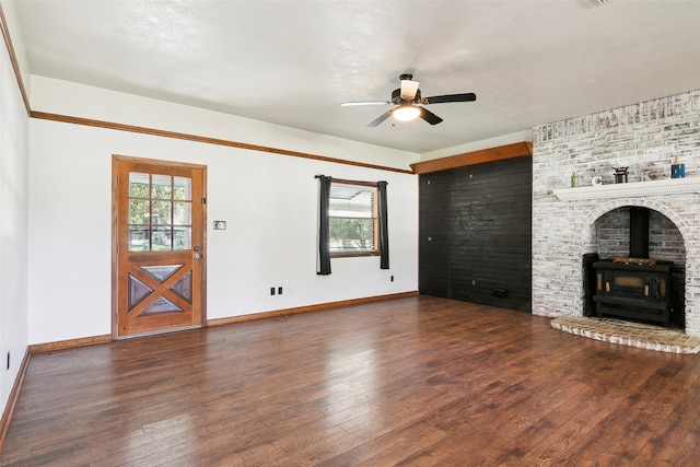 unfurnished living room with dark wood-type flooring, ceiling fan, and a wood stove