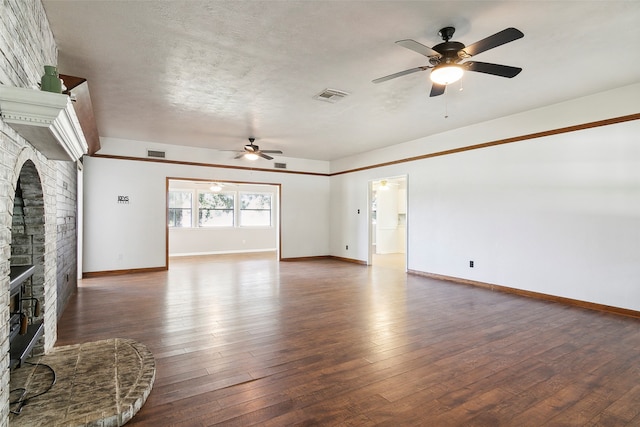 unfurnished living room featuring a stone fireplace, a textured ceiling, dark wood-type flooring, and ceiling fan