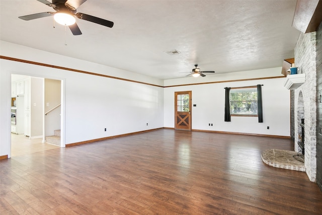 unfurnished living room featuring ceiling fan, a large fireplace, and dark hardwood / wood-style flooring