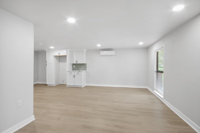 unfurnished living room featuring an AC wall unit and light wood-type flooring