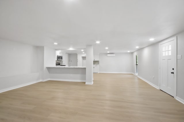 basement with light hardwood / wood-style flooring, a wall mounted AC, and sink