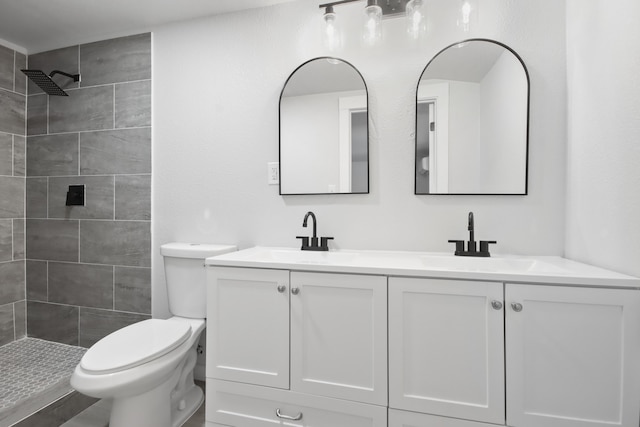 bathroom with toilet, vanity, and tiled shower