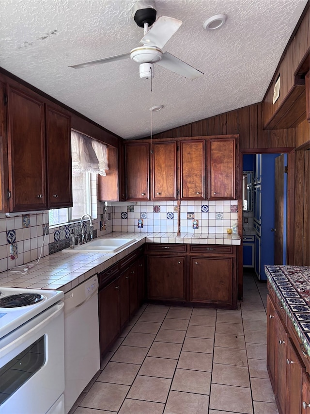 kitchen with wooden walls, white appliances, tile countertops, light tile patterned floors, and a textured ceiling