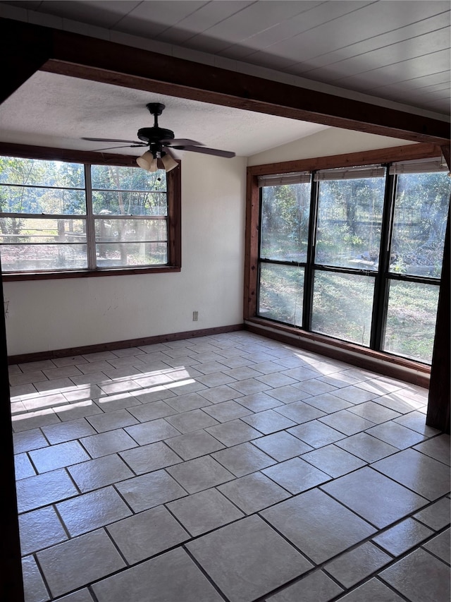 empty room featuring ceiling fan and vaulted ceiling with beams