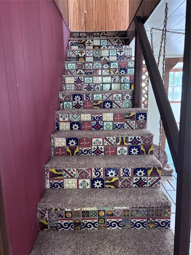 staircase featuring wood walls and carpet flooring