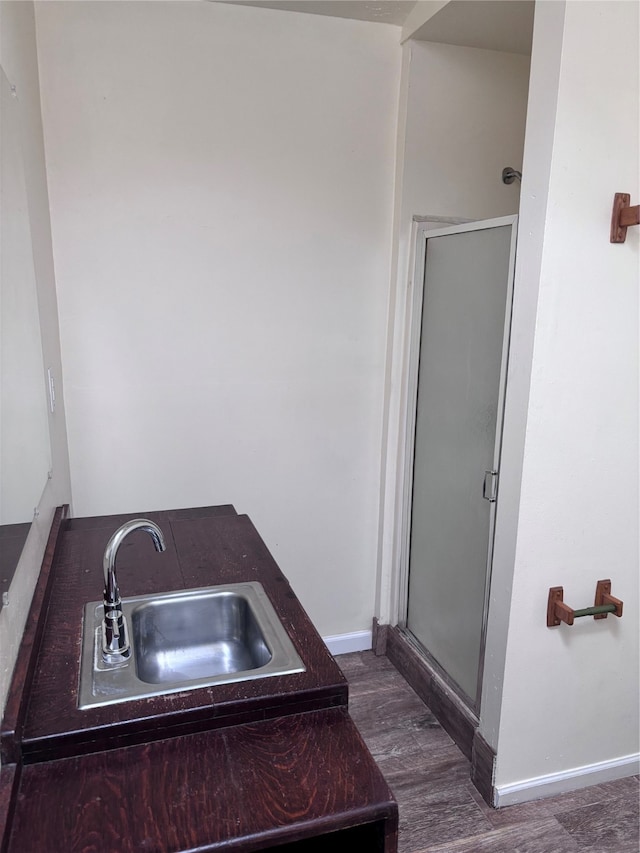 bathroom with hardwood / wood-style flooring, walk in shower, and sink