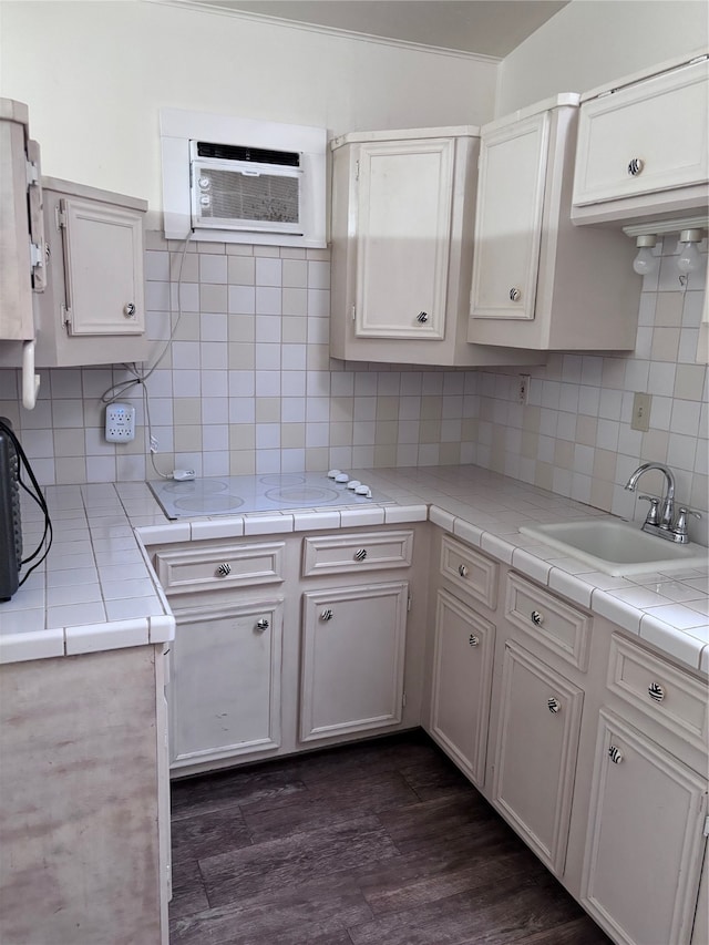 kitchen with white cabinets, sink, tile countertops, dark hardwood / wood-style flooring, and an AC wall unit