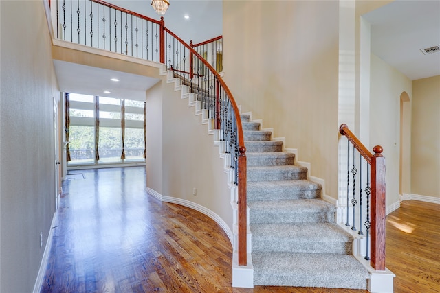 stairs featuring wood-type flooring and a towering ceiling