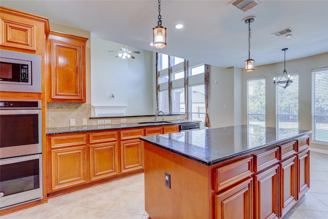 kitchen featuring ceiling fan with notable chandelier, appliances with stainless steel finishes, a center island, and a healthy amount of sunlight