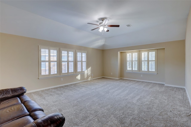 unfurnished living room featuring ceiling fan, a healthy amount of sunlight, light colored carpet, and vaulted ceiling