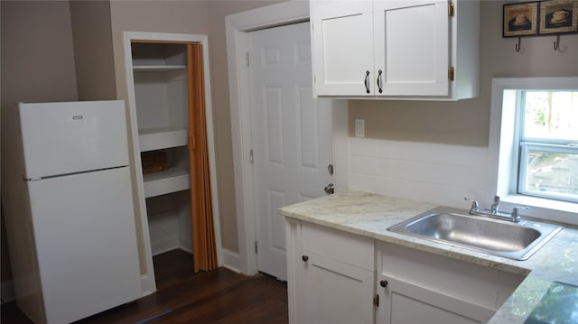 kitchen featuring white fridge, dark wood-type flooring, sink, and white cabinets