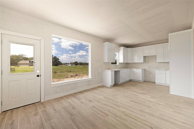 kitchen featuring a textured ceiling, white cabinetry, and light hardwood / wood-style flooring