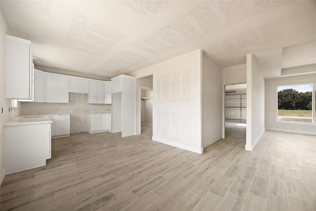 kitchen featuring white cabinets, a textured ceiling, and light hardwood / wood-style flooring