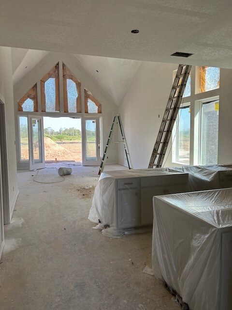 bedroom featuring lofted ceiling, concrete flooring, and a textured ceiling