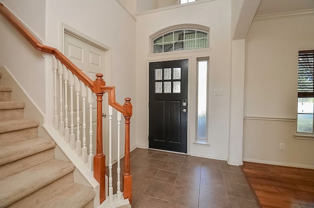 entryway with a towering ceiling, crown molding, and dark hardwood / wood-style flooring