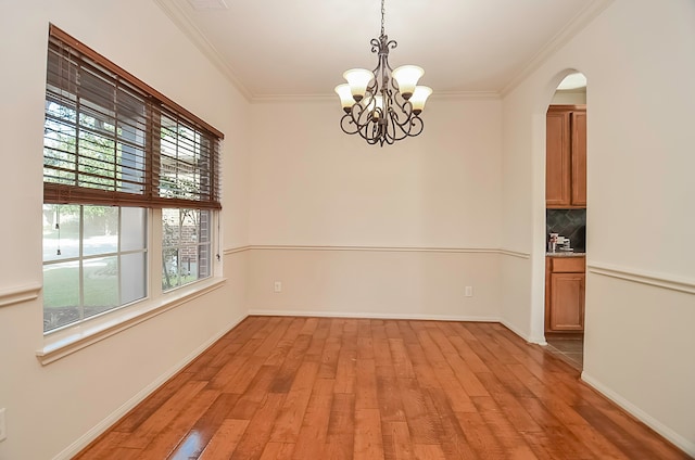 empty room featuring ornamental molding, a notable chandelier, and light hardwood / wood-style floors