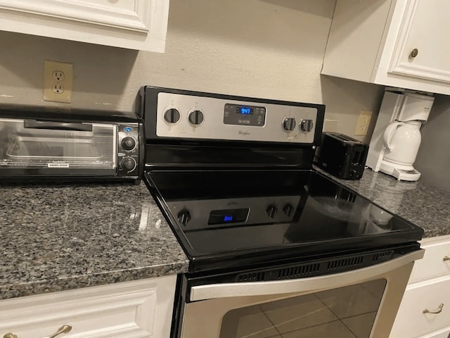 kitchen featuring white cabinets, stainless steel electric range oven, and tile patterned floors