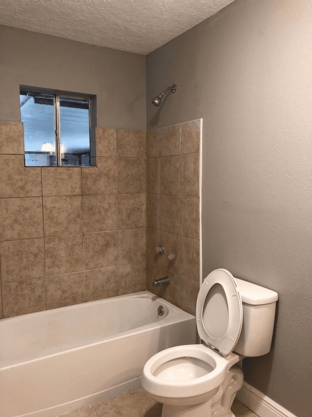 bathroom featuring tiled shower / bath, a textured ceiling, and toilet