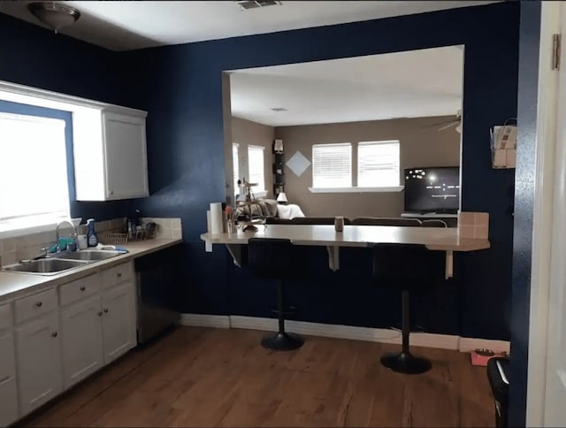 kitchen with ceiling fan, hardwood / wood-style floors, sink, kitchen peninsula, and white cabinetry