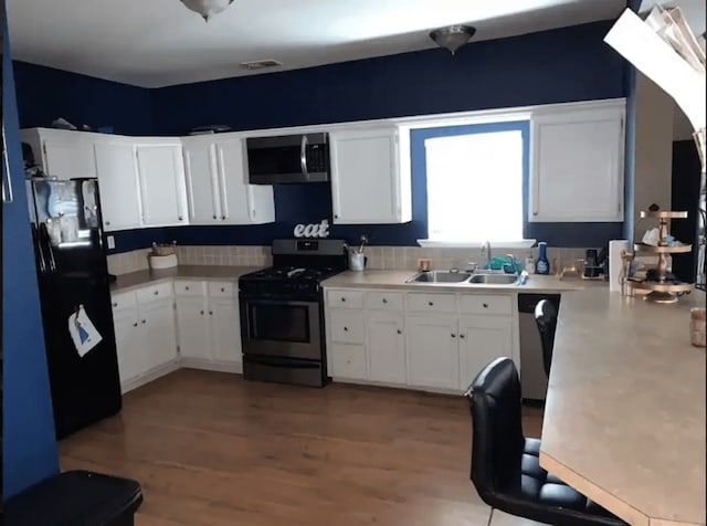 kitchen with wood-type flooring, white cabinetry, sink, and stainless steel appliances