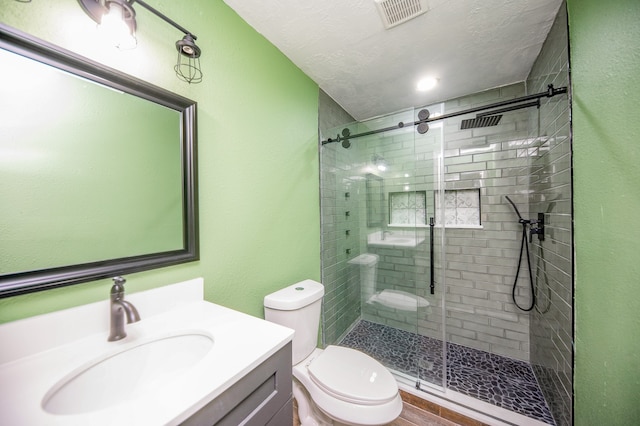 bathroom with vanity, hardwood / wood-style flooring, toilet, walk in shower, and a textured ceiling