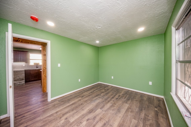 empty room featuring wood-type flooring and a textured ceiling