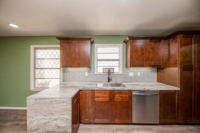 kitchen featuring a healthy amount of sunlight, sink, stainless steel dishwasher, and light hardwood / wood-style flooring