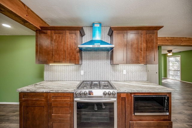 kitchen featuring light stone countertops, appliances with stainless steel finishes, wall chimney exhaust hood, a textured ceiling, and ceiling fan