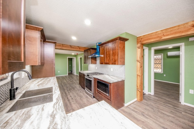 kitchen with wall chimney exhaust hood, stainless steel range oven, light wood-type flooring, and sink