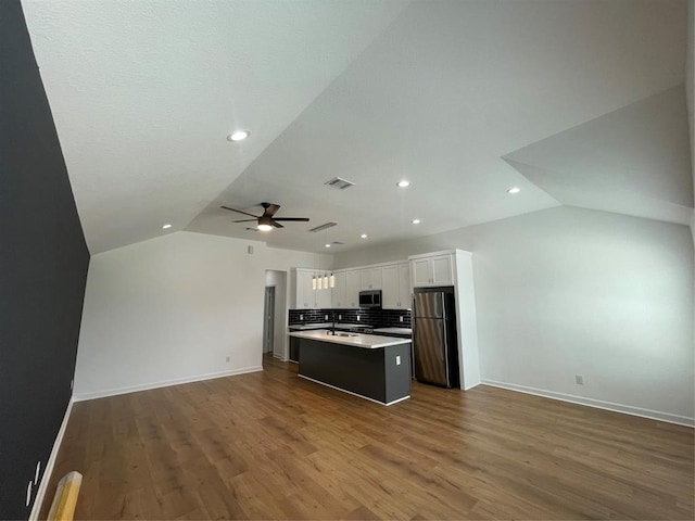 kitchen with a kitchen island, lofted ceiling, stainless steel appliances, white cabinets, and dark wood-type flooring