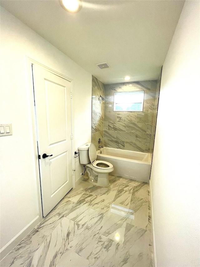 bathroom featuring tiled shower / bath combo and toilet