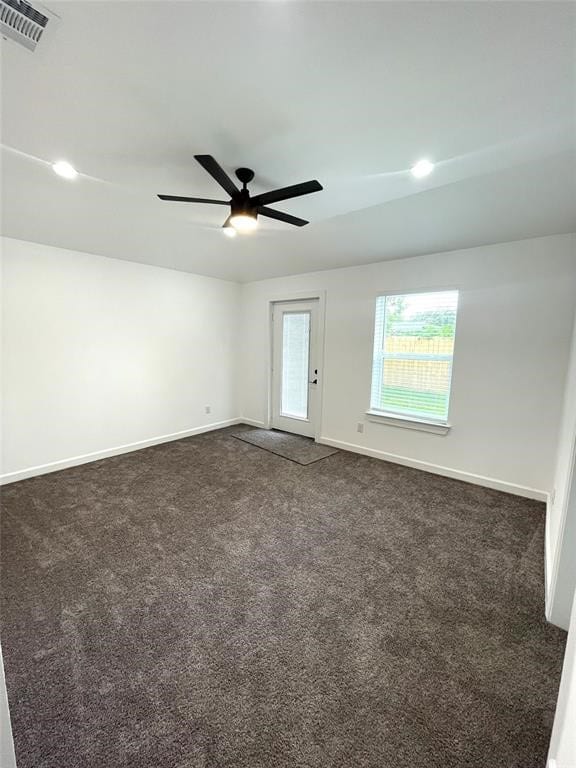 unfurnished room with dark carpet and ceiling fan