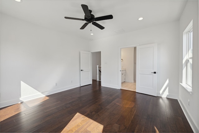 unfurnished bedroom with ceiling fan, ensuite bath, and dark wood-type flooring