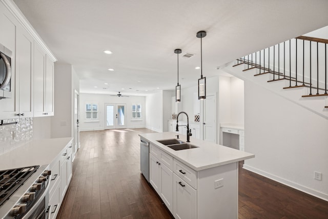 kitchen with dark hardwood / wood-style flooring, a center island with sink, sink, stainless steel appliances, and white cabinets