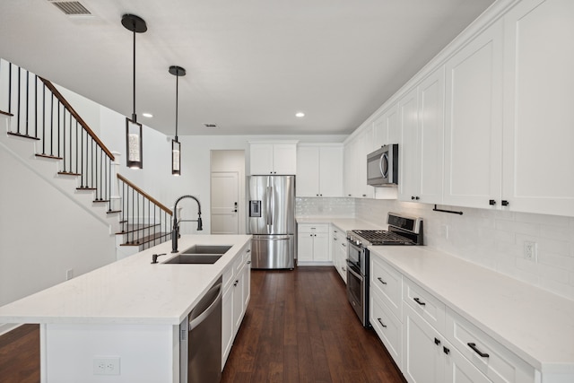 kitchen featuring a kitchen island with sink, stainless steel appliances, sink, dark hardwood / wood-style flooring, and decorative light fixtures