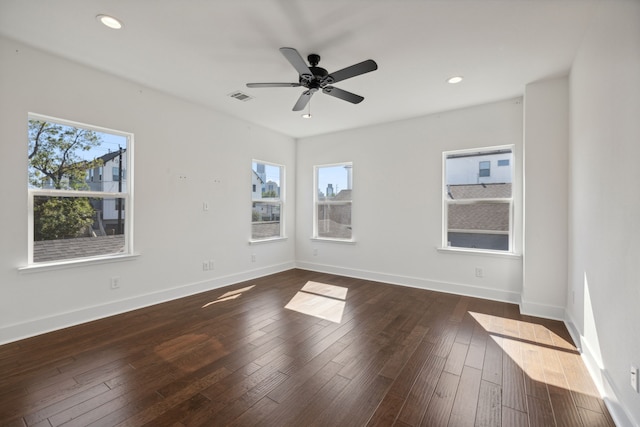 empty room with a healthy amount of sunlight, ceiling fan, and dark hardwood / wood-style floors