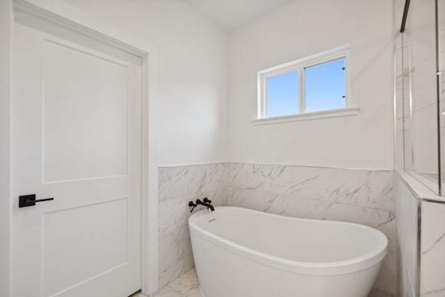 bathroom with a tub to relax in and tile walls