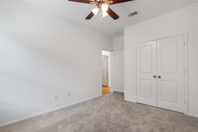 unfurnished bedroom featuring a closet, light colored carpet, and ceiling fan