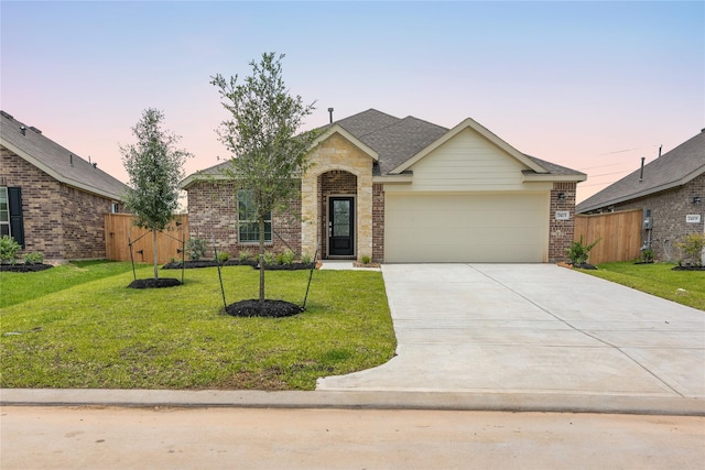 view of front of home with a garage, driveway, a lawn, and brick siding