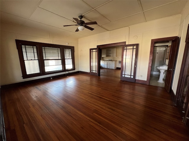 unfurnished living room with a drop ceiling, sink, dark hardwood / wood-style flooring, and ceiling fan