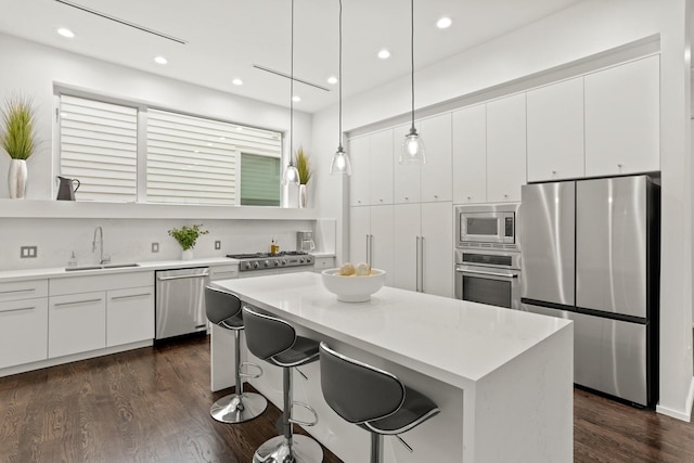 kitchen with white cabinetry, sink, dark hardwood / wood-style flooring, pendant lighting, and appliances with stainless steel finishes