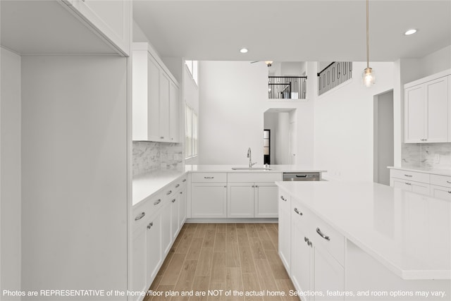 kitchen with hanging light fixtures, sink, tasteful backsplash, stainless steel dishwasher, and white cabinetry