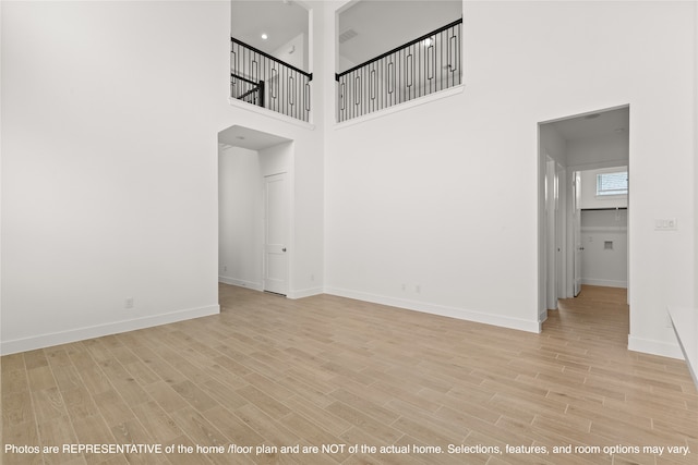 interior space with light wood-type flooring and a towering ceiling