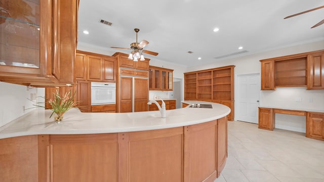 kitchen with paneled built in fridge, crown molding, oven, and kitchen peninsula