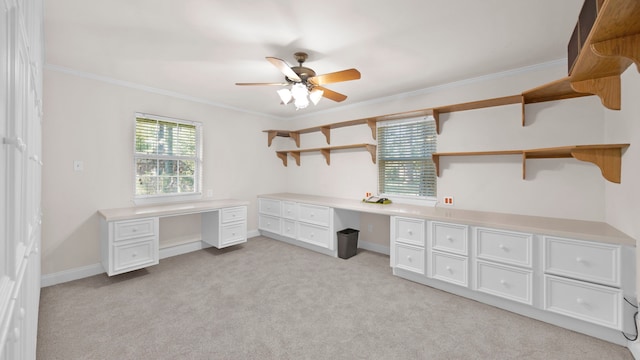 unfurnished office with light carpet, built in desk, crown molding, and ceiling fan