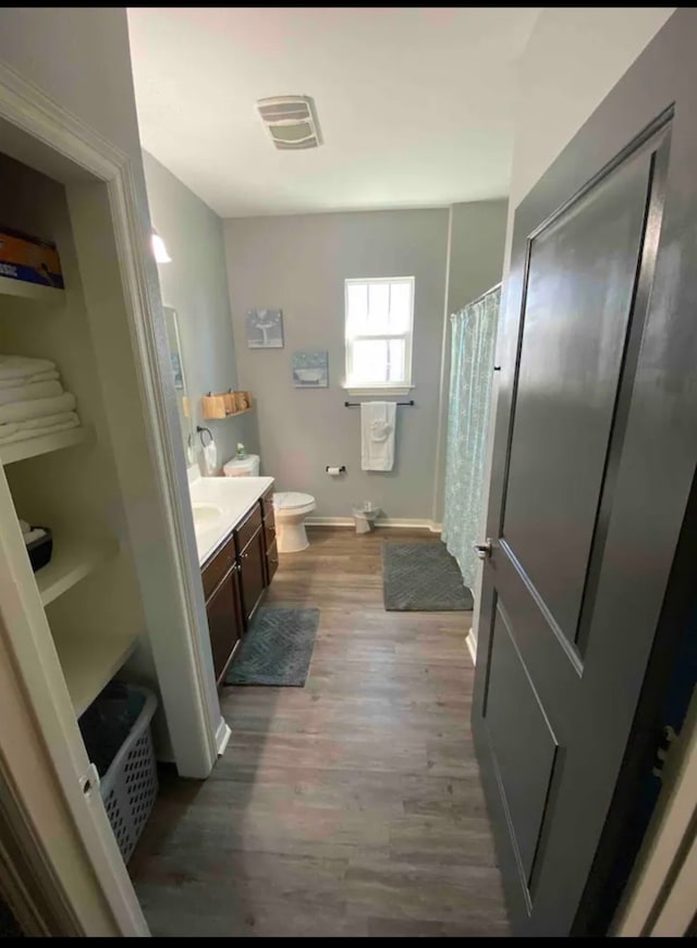 bathroom with wood-type flooring, a shower with shower curtain, vanity, and toilet