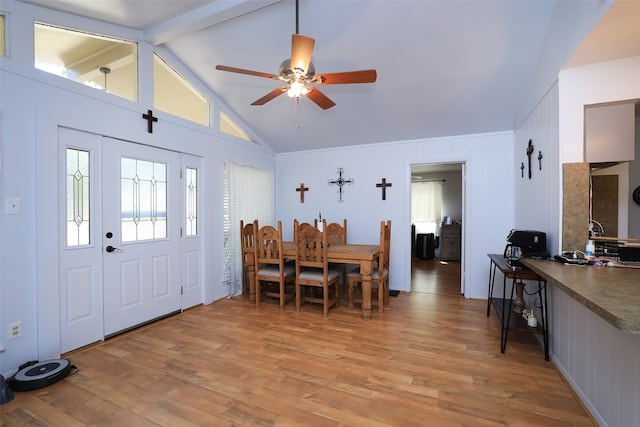 dining space with ceiling fan, vaulted ceiling with beams, and light hardwood / wood-style flooring