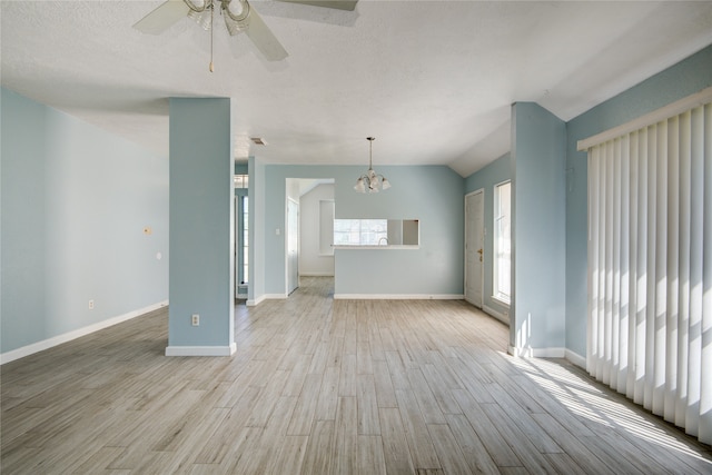 unfurnished living room with ceiling fan with notable chandelier, a textured ceiling, light hardwood / wood-style flooring, and vaulted ceiling