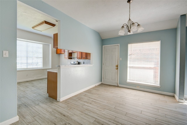 interior space featuring light wood-type flooring, a notable chandelier, and vaulted ceiling