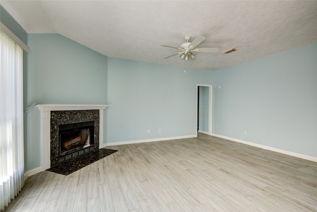 unfurnished living room with a high end fireplace, light hardwood / wood-style flooring, and a textured ceiling